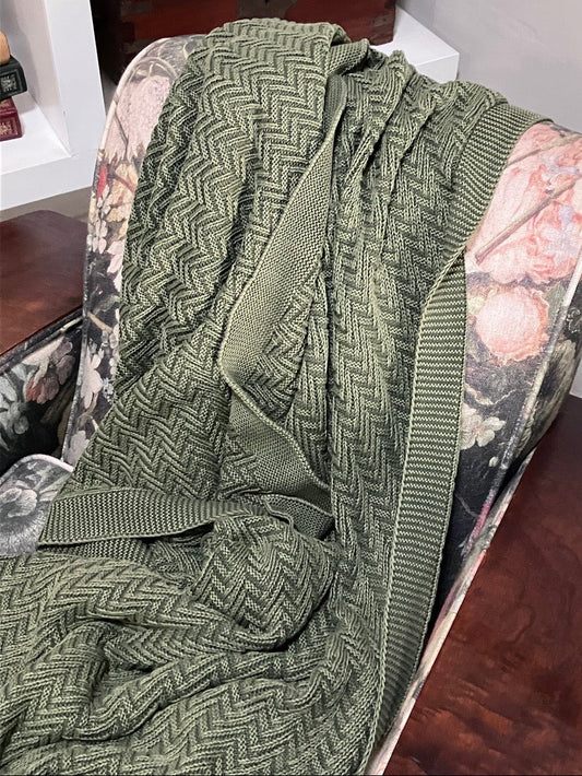 Green plain knitted throw on a floral-patterned and wooden chair