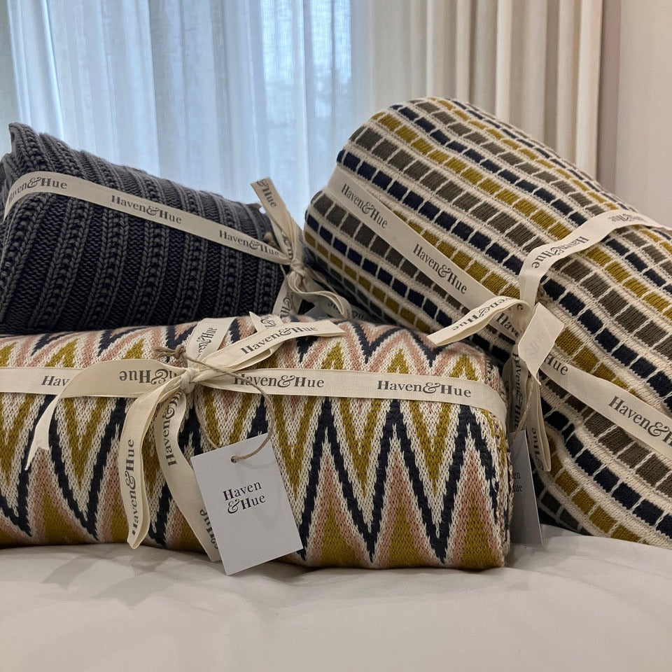 Three patterned throws with ribbons and tags on a neutral background