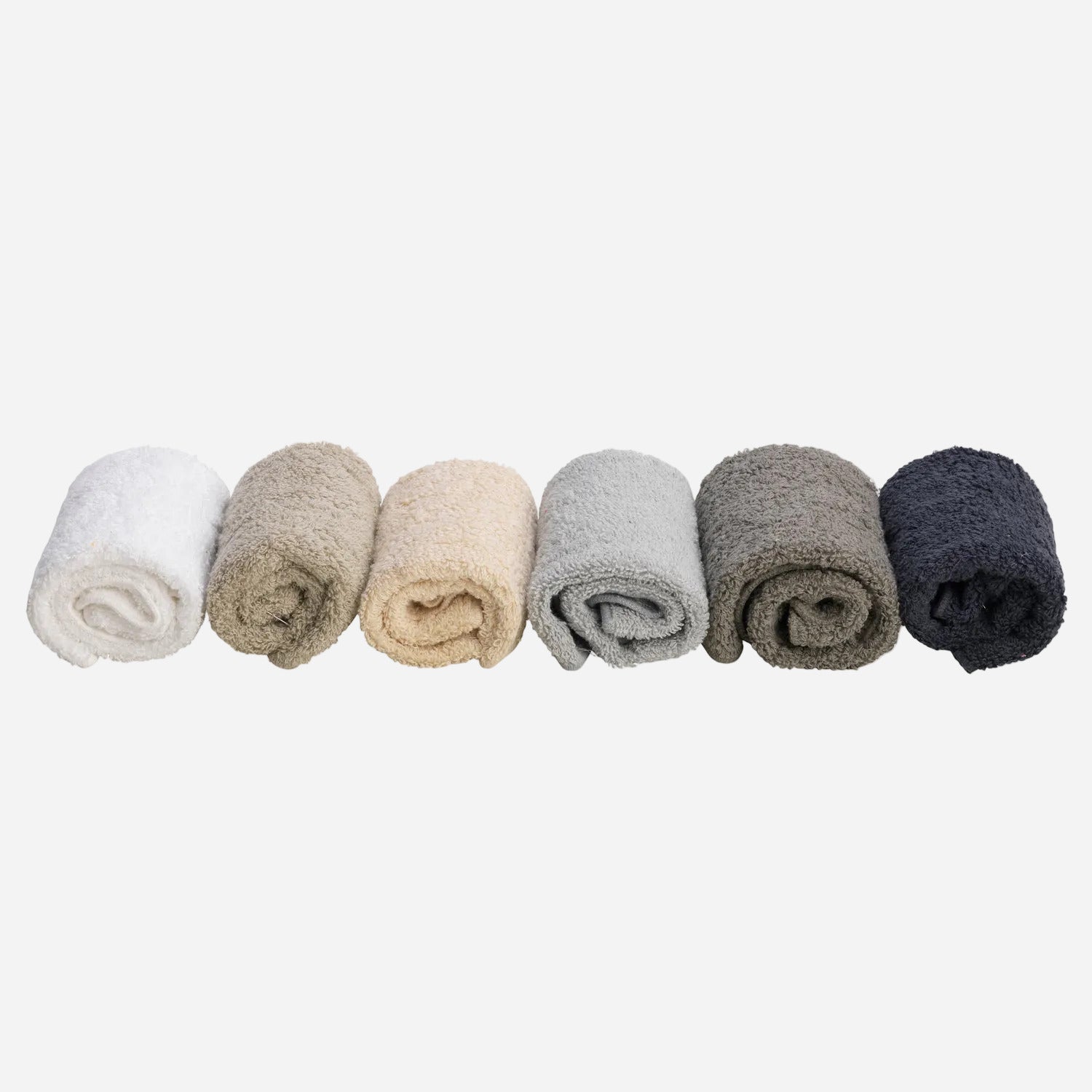 Set of six rolled-up face cloths in white, beige, gray, and black on a white background